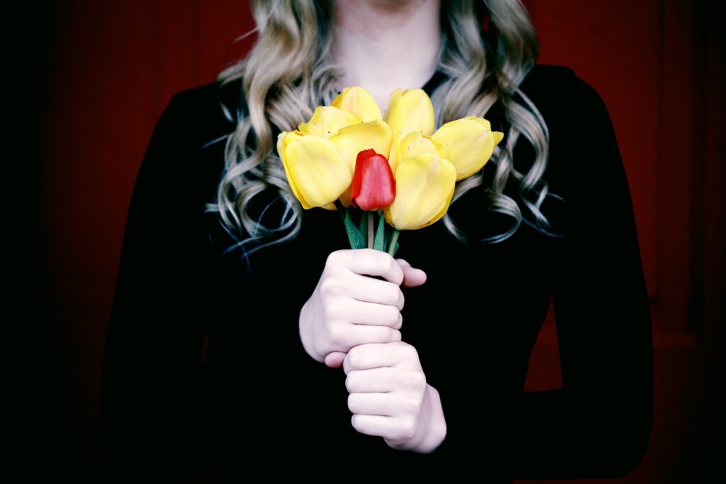 Woman holding yellow and red tulips