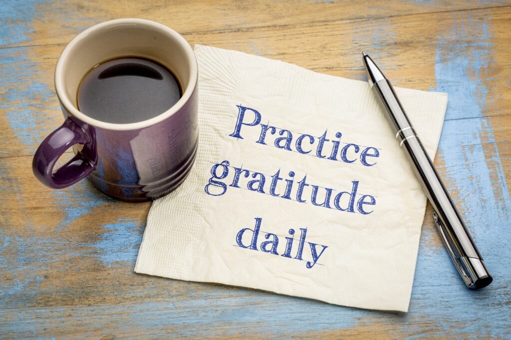 Coffee cup and napkin that has practice gratitude daily on it.