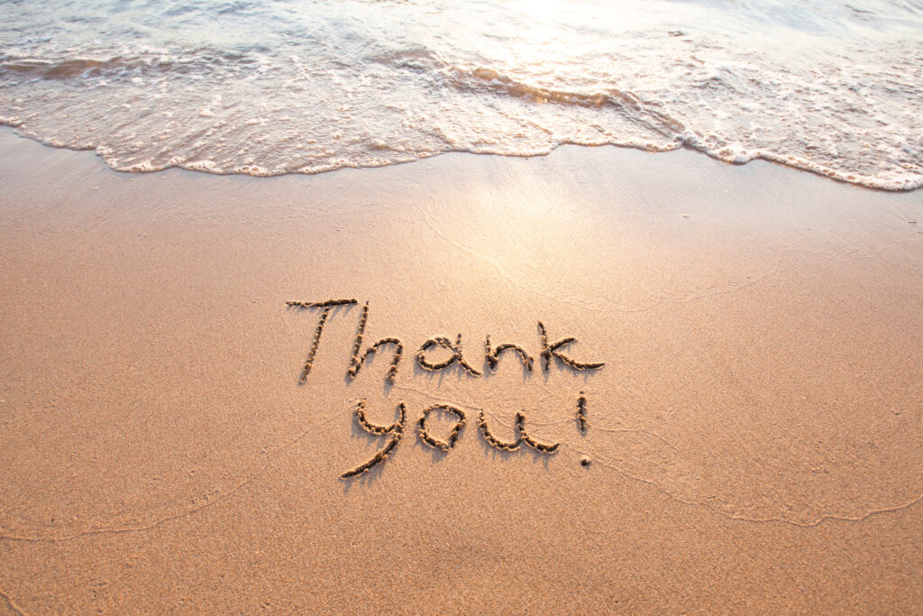 Thank you written into sand on the beach