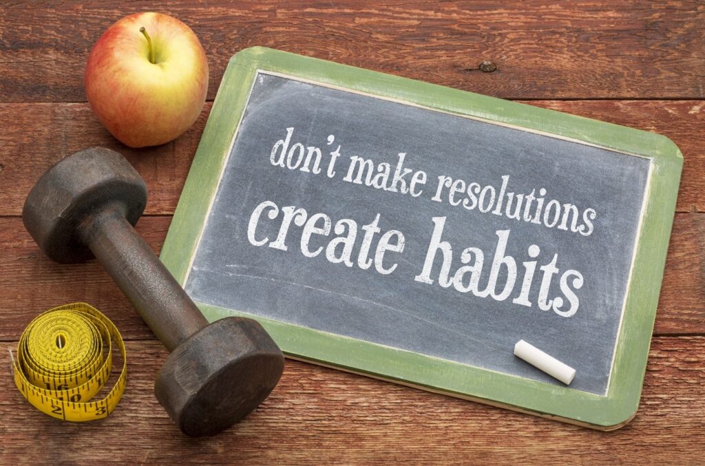 Image of a chalk board with the words "don't make resolutions create habits"