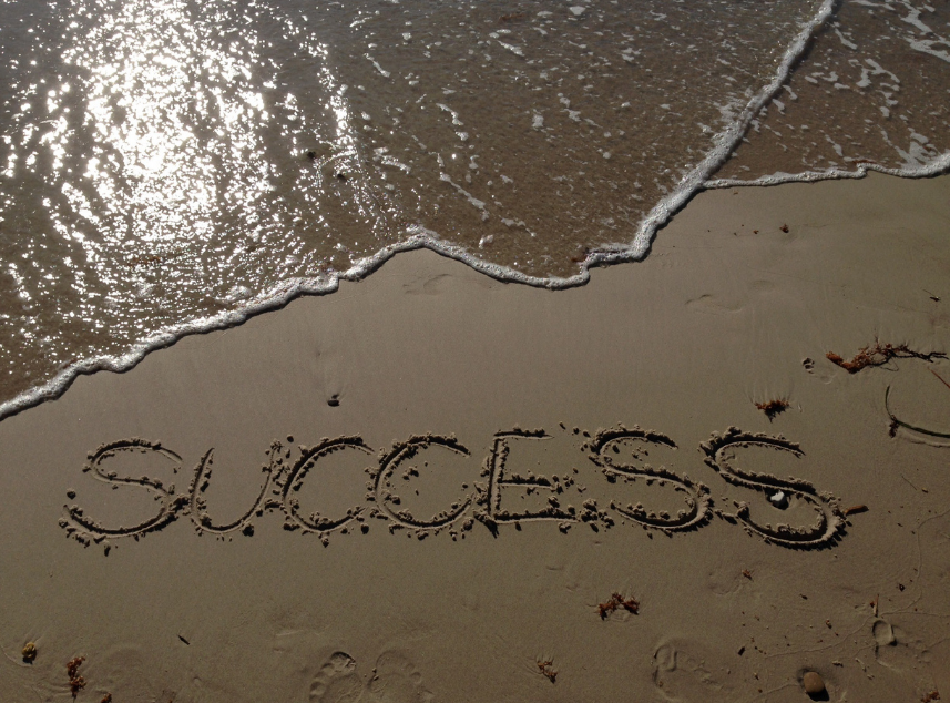 The word success written in the sand at the beach.