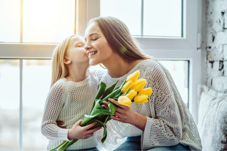 Girl handing flowers to her mother.