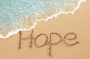 Hope written in the sand by the ocean